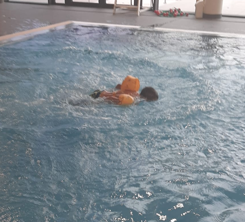 Un enfant nage avec des brassards dans la piscine